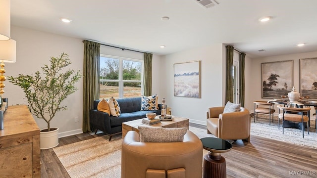 sitting room with baseboards, visible vents, wood finished floors, and recessed lighting