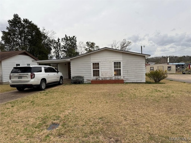 view of front of house with a carport, a front lawn, and driveway