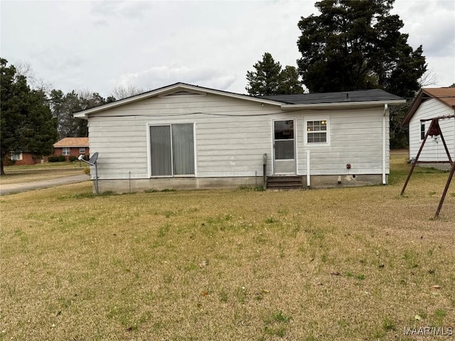 rear view of property featuring entry steps and a lawn