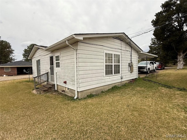 view of side of home with entry steps and a lawn