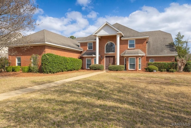 greek revival house featuring brick siding and a front lawn