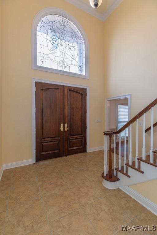 entrance foyer with baseboards, a high ceiling, stairway, and crown molding