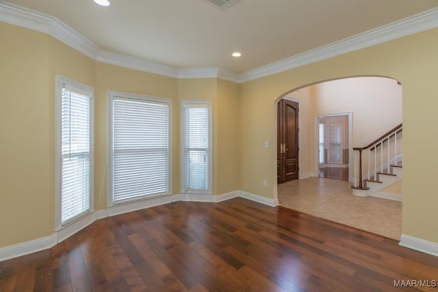 spare room featuring plenty of natural light, baseboards, arched walkways, hardwood / wood-style flooring, and ornamental molding