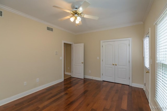 unfurnished bedroom with crown molding, a closet, visible vents, wood finished floors, and baseboards