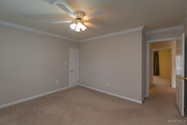 spare room featuring a ceiling fan, light colored carpet, crown molding, and baseboards