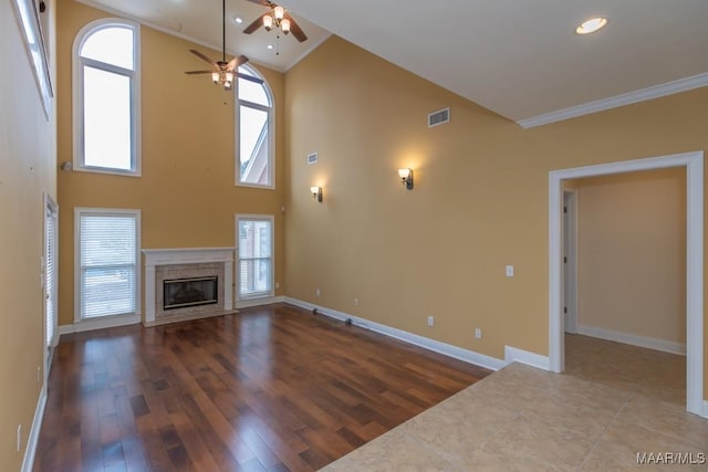 unfurnished living room featuring a high end fireplace, visible vents, crown molding, and wood finished floors