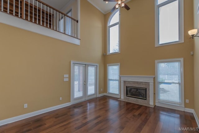 unfurnished living room featuring plenty of natural light, a fireplace, baseboards, and wood finished floors