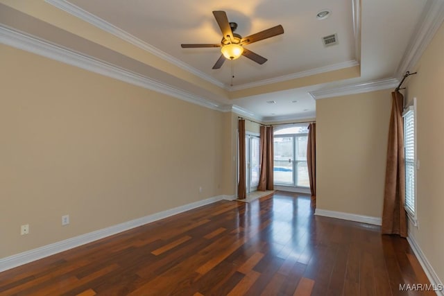 empty room with dark wood-style flooring, crown molding, a raised ceiling, visible vents, and baseboards