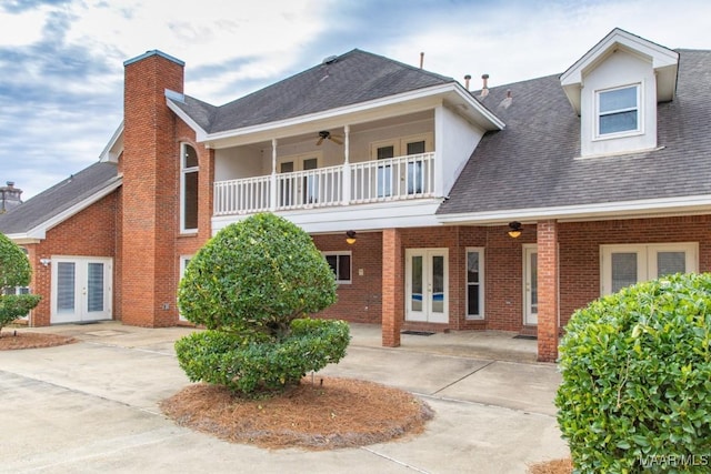 view of front of home featuring a balcony, ceiling fan, roof with shingles, french doors, and brick siding