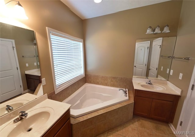 bathroom featuring tile patterned flooring, two vanities, a garden tub, and a sink