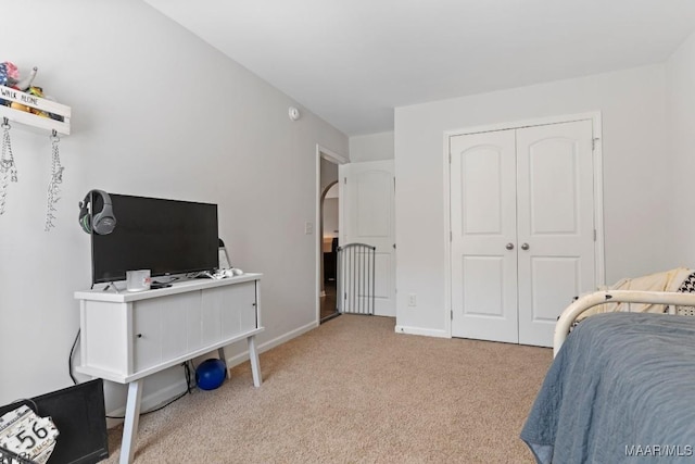 carpeted bedroom with baseboards, arched walkways, and a closet