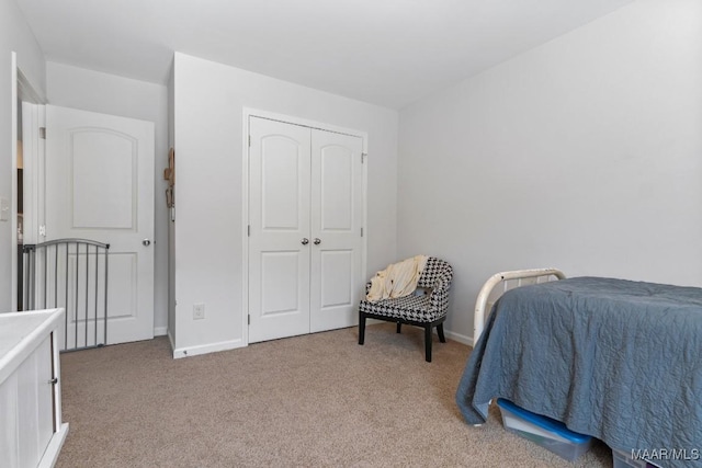 bedroom featuring baseboards, a closet, and light colored carpet