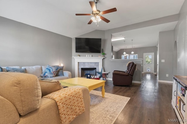 living area with baseboards, a tiled fireplace, lofted ceiling, ceiling fan, and dark wood-style flooring