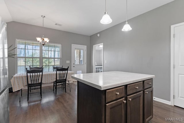 kitchen with dark brown cabinets, hanging light fixtures, dark wood finished floors, and light countertops