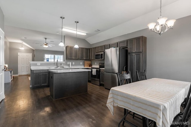 kitchen featuring appliances with stainless steel finishes, vaulted ceiling, a sink, and dark wood-style floors