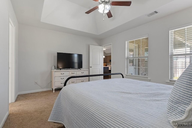 bedroom featuring visible vents, baseboards, a raised ceiling, light colored carpet, and ceiling fan