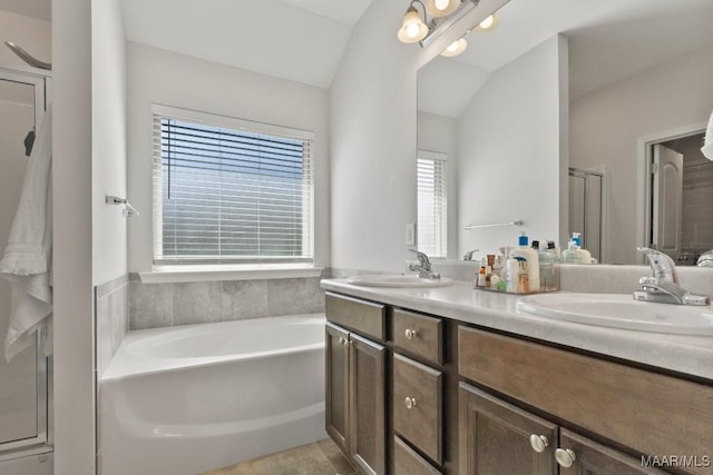 bathroom featuring lofted ceiling, double vanity, a sink, and a bath