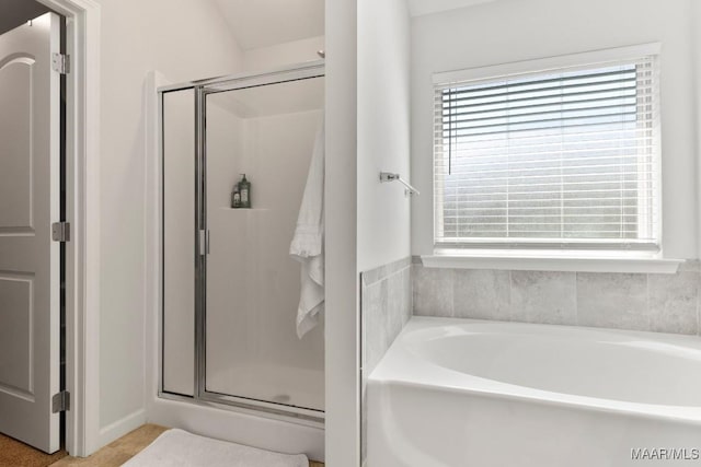 bathroom with a wealth of natural light, a garden tub, and a shower stall