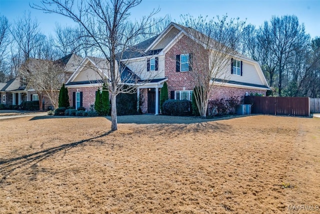 view of front of home featuring brick siding, fence, and a gambrel roof