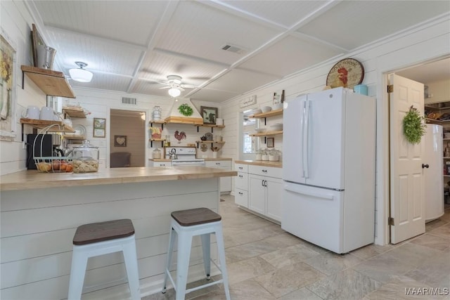 kitchen featuring white appliances, visible vents, white cabinets, a kitchen bar, and open shelves