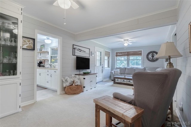 living area with light colored carpet, crown molding, and ceiling fan