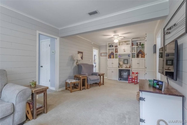 interior space featuring a ceiling fan, light colored carpet, crown molding, and visible vents