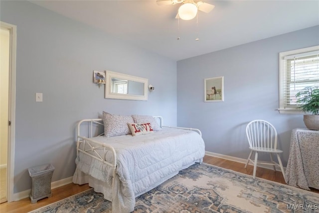 bedroom featuring wood finished floors, a ceiling fan, and baseboards