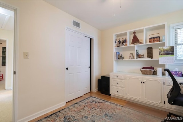 office area with light wood finished floors, baseboards, and visible vents