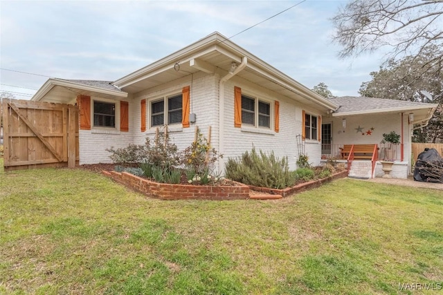 view of side of home with brick siding, a lawn, and fence