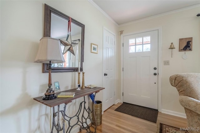 foyer featuring light wood-type flooring, crown molding, and baseboards