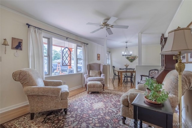 sitting room featuring ceiling fan with notable chandelier, ornamental molding, wood finished floors, and baseboards