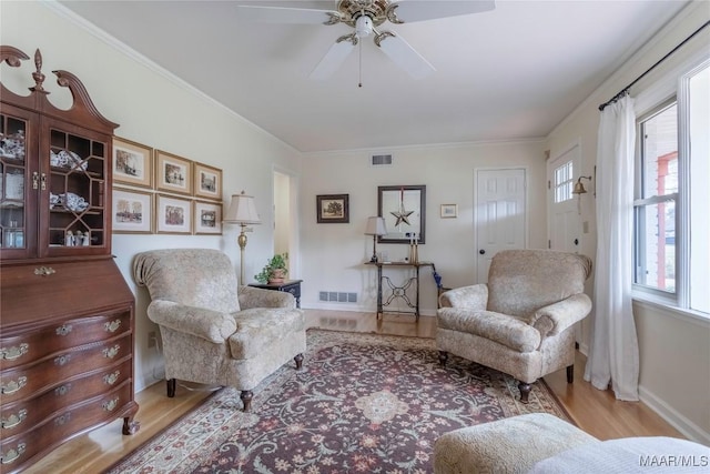 living area with visible vents, crown molding, and wood finished floors