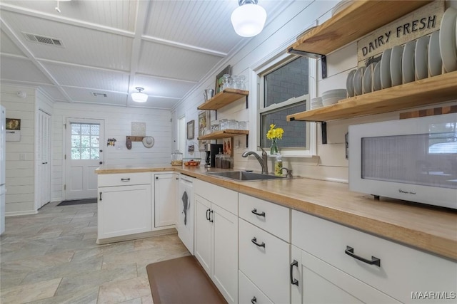 kitchen with visible vents, white cabinets, white microwave, open shelves, and a sink