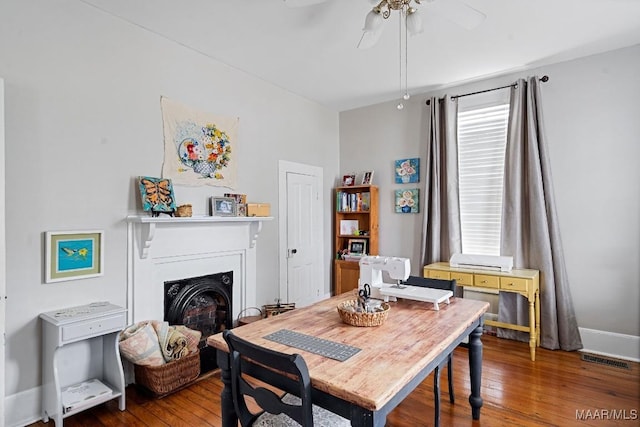 dining space featuring baseboards, wood-type flooring, a fireplace, and a healthy amount of sunlight