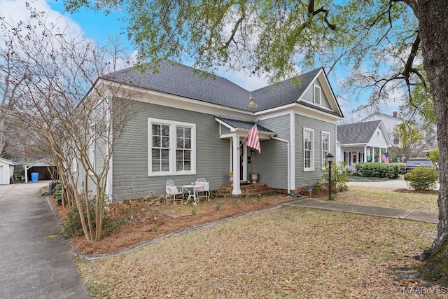 view of front of home with a shingled roof, an outdoor structure, and a detached garage