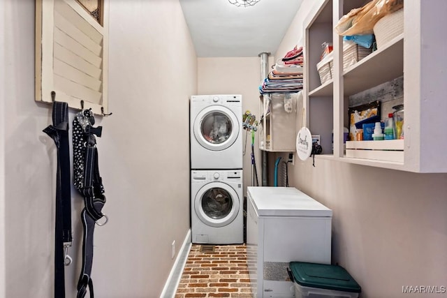 laundry room with baseboards, laundry area, brick floor, and stacked washer / drying machine