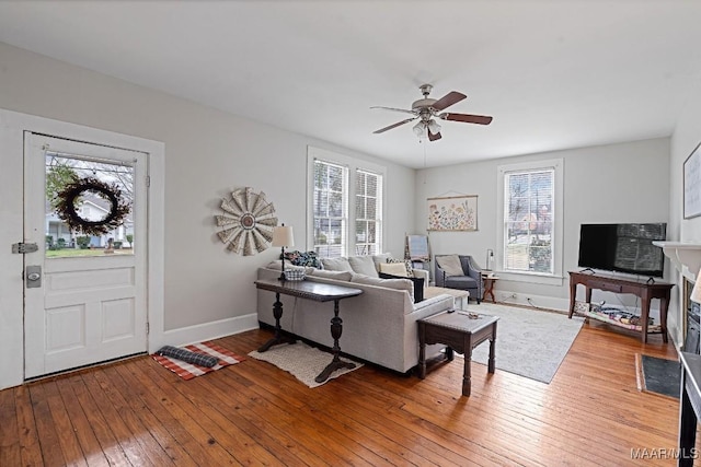 living area with light wood-type flooring, a ceiling fan, and baseboards