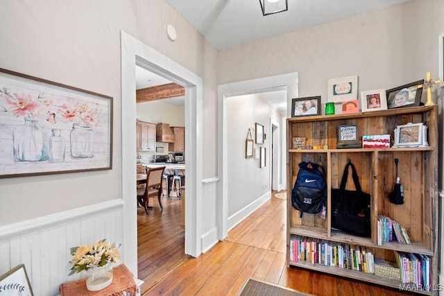 corridor featuring light wood-type flooring and wainscoting