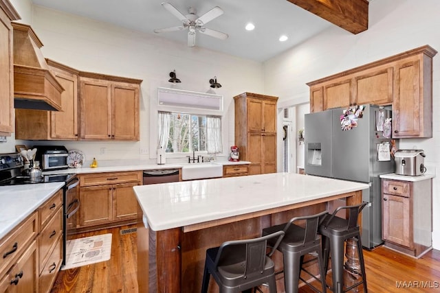 kitchen featuring wood finished floors, appliances with stainless steel finishes, a kitchen bar, and a sink