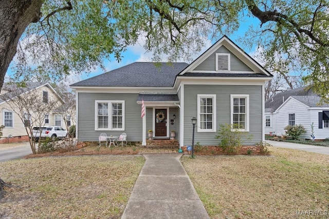 view of front facade featuring roof with shingles and a front lawn