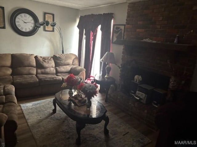 living area with a brick fireplace and wood finished floors