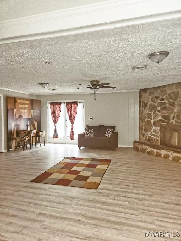 unfurnished living room with ceiling fan, a textured ceiling, visible vents, and wood finished floors