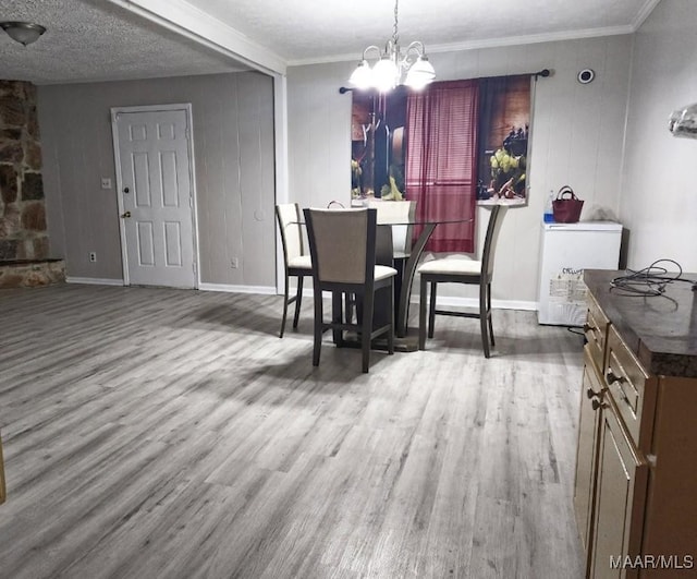 dining area with crown molding, a textured ceiling, wood finished floors, and a notable chandelier