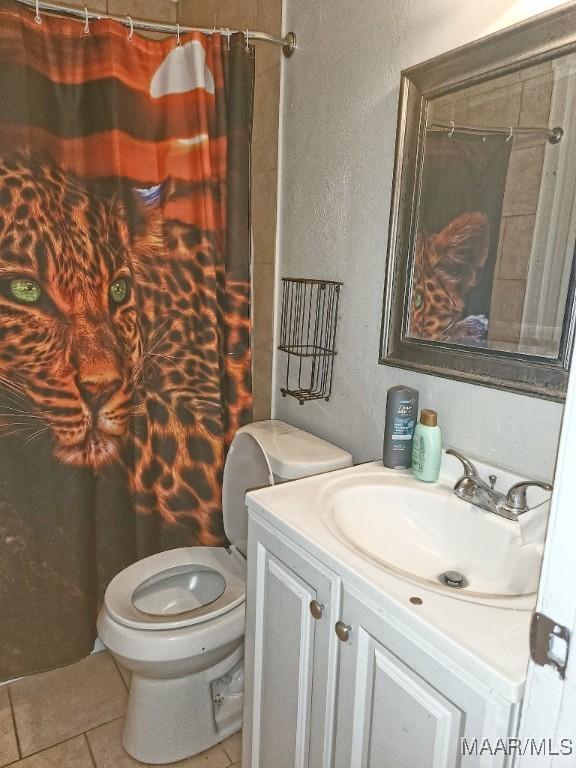 full bathroom with toilet, curtained shower, tile patterned flooring, and vanity