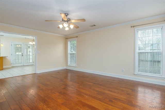 unfurnished room with wood finished floors, visible vents, a ceiling fan, baseboards, and ornamental molding