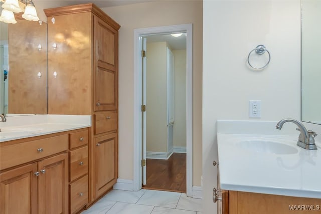 full bathroom with an inviting chandelier, two vanities, and a sink