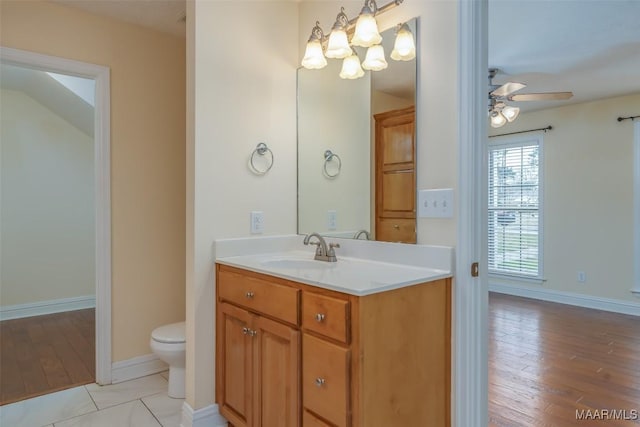 bathroom featuring toilet, a ceiling fan, vanity, wood finished floors, and baseboards