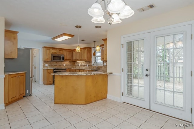 kitchen with a peninsula, a sink, visible vents, appliances with stainless steel finishes, and tasteful backsplash