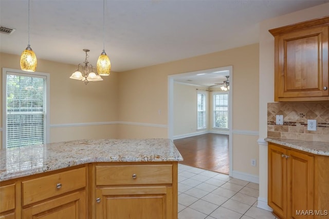 kitchen featuring light stone countertops, tasteful backsplash, a wealth of natural light, and light tile patterned flooring