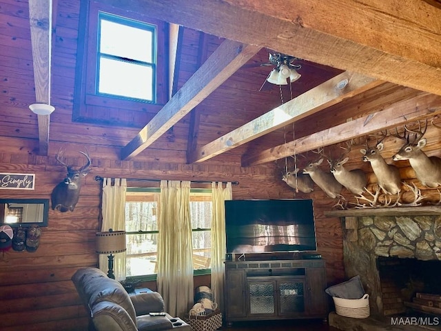 living room with rustic walls, a towering ceiling, ceiling fan, a stone fireplace, and beam ceiling